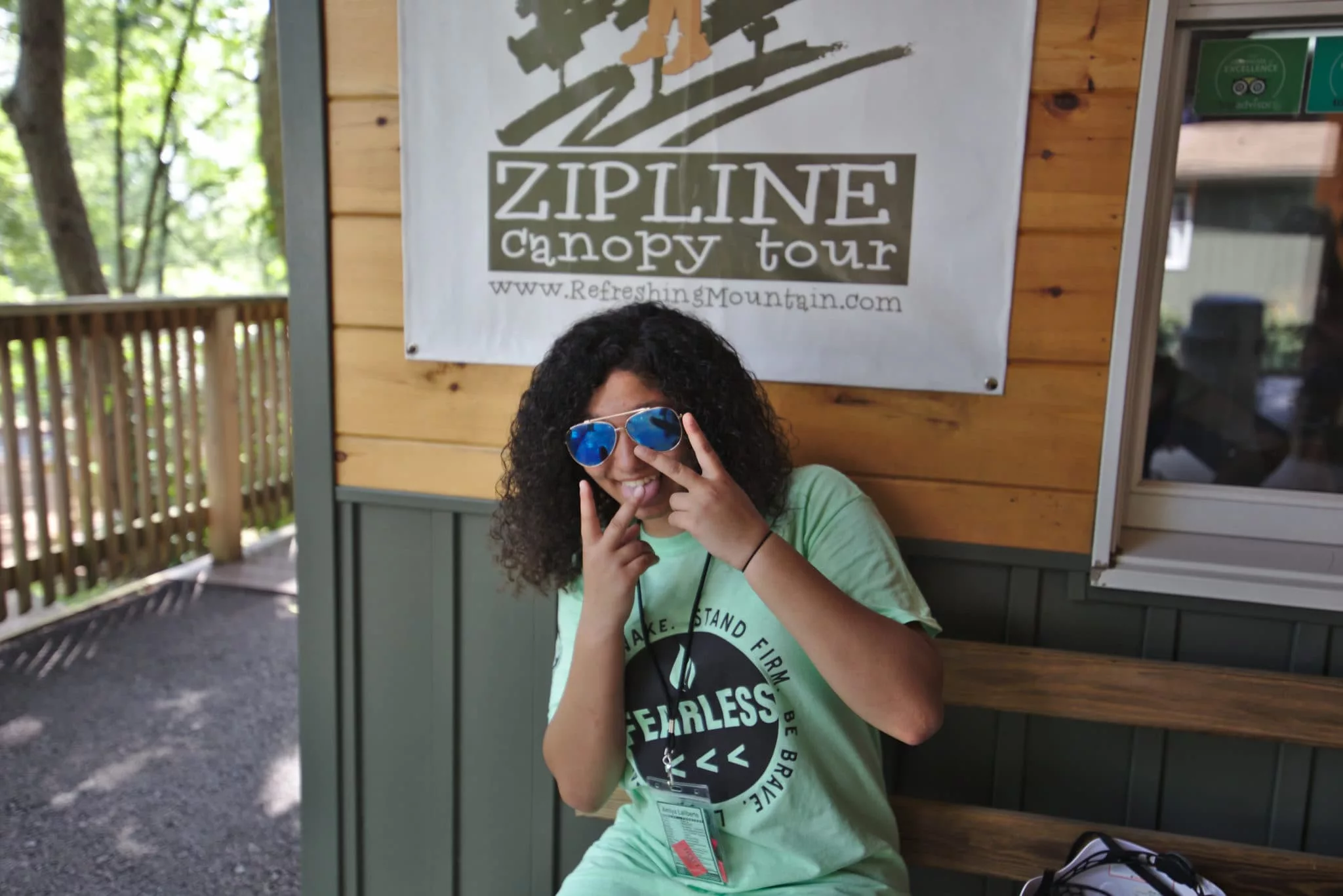 A-Girl-Taking-A-Picture-In-Front-Of-The-Office-For-Refreshing-Mountains-Zipline-Canopy-Tour A Girl Posing For A Picture In Front Of Refreshing Mountain'S Office For Zipline Canopy Tours