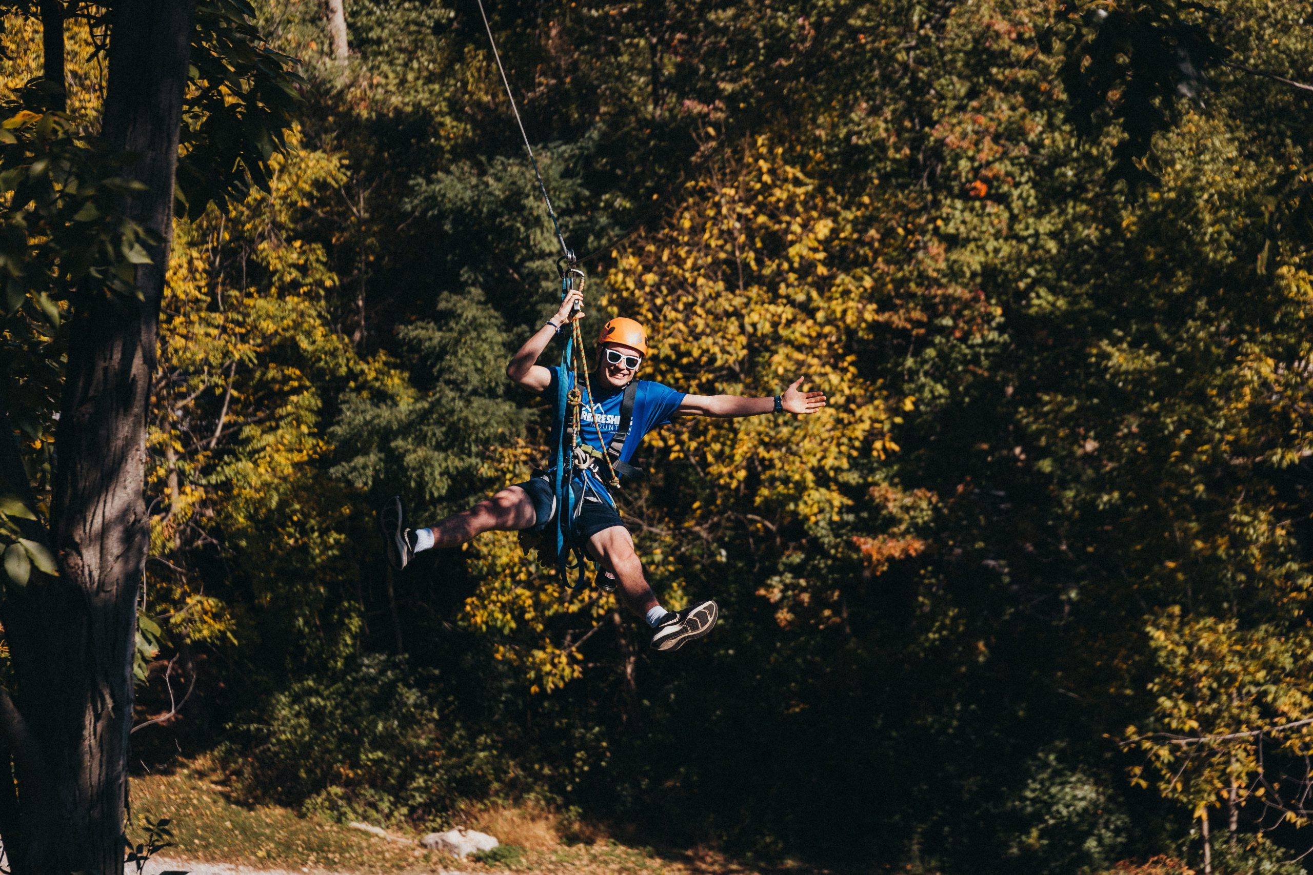 Man Smiling And Waving Arm While Ziplining