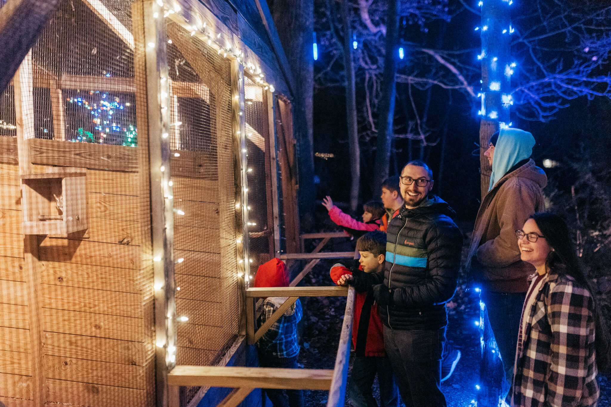 People Inspecting Christmas Lights While On A Refreshing Mountain Christmas Walk Experience