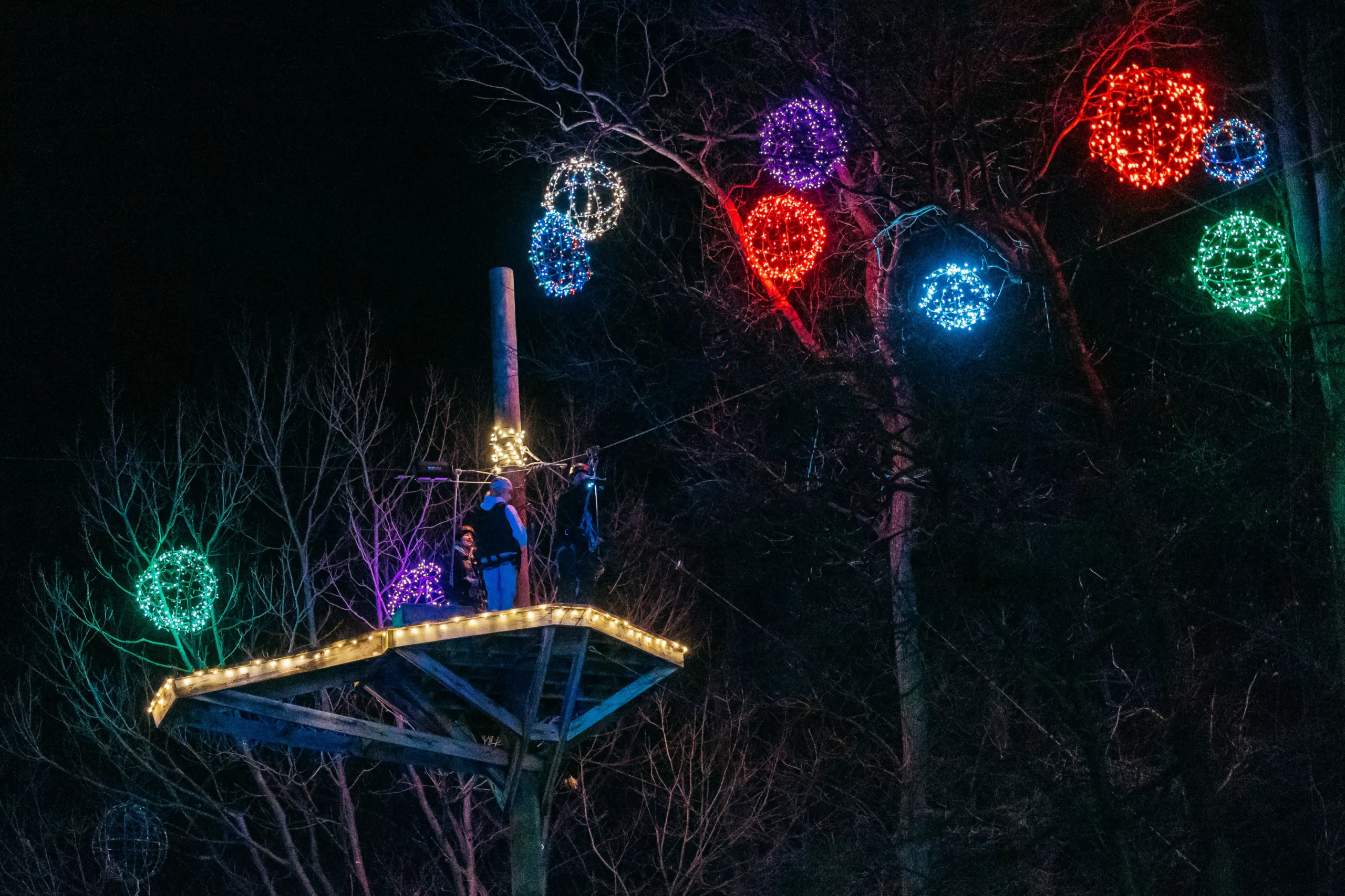 Aerial Christmas Light Zipline Group Balls Of Christmas Lights Hanging From Trees At Refreshing Mountain Retreat And Adventure